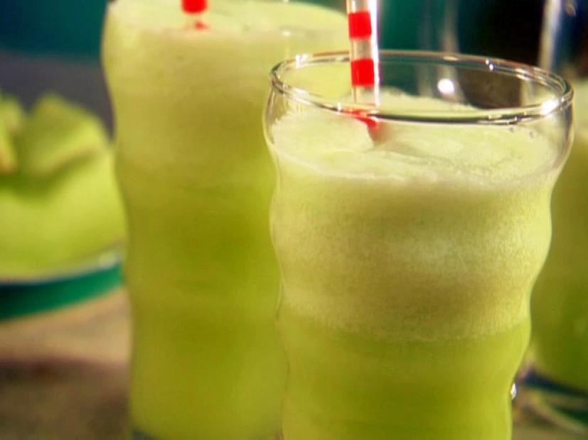 Glasses of Honey Dew Tropic Freeze in wavy clear glasses next to cubed slices of honey dew on a plate