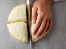 A cavatelli how-to displaying a hand holding dough as it is being cut into quarters