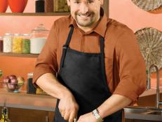 Next Food Network Star Finalist Alexis Hernandez smiling while wearing a brown shirt and black apron