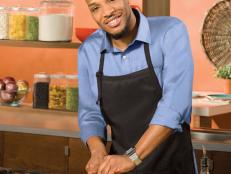Next Food Network Star Finalist Darrell Smith smiling while wearing a blue button down shirt and black apron