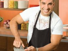Next Food Network Star Finalist Herb Mesa smiling while wearing a t-shirt and black apron