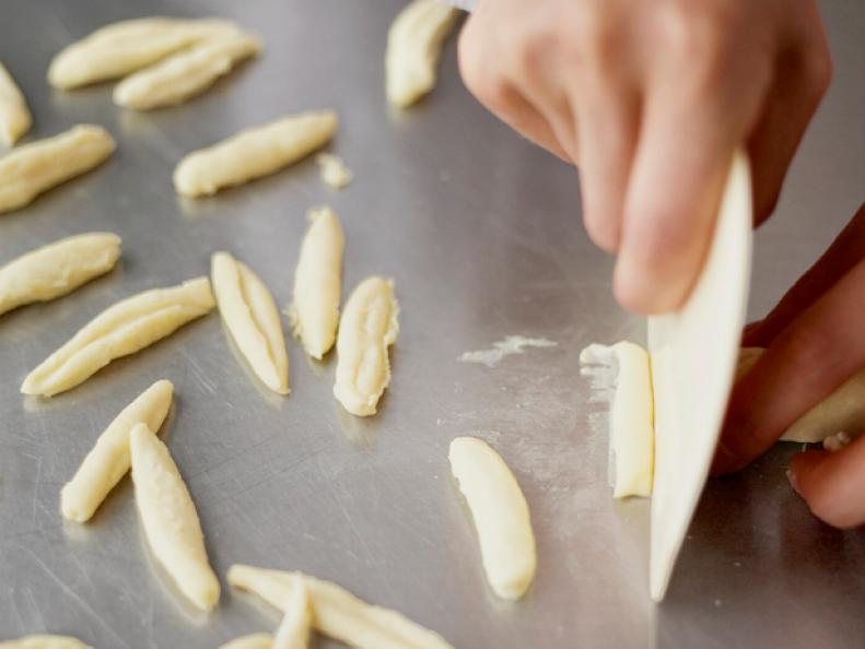 A cavatelli how-to  displaying pieces of dough being cut from a roll of dough