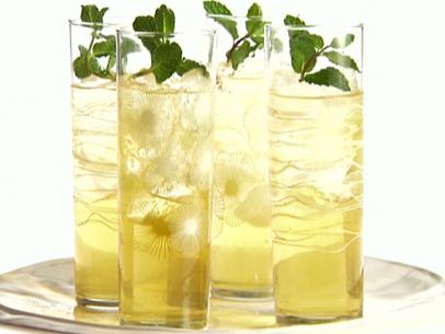 Four glasses of apple mint punch are served with a fresh mint garnish.