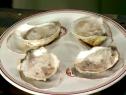 Oysters with prosecco granita that are served on a plate in their shells with the frozen granita on top.