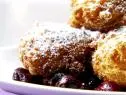 Italian donuts are served wtih powdered sugar and over cherry sauce.