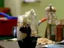 A close up of a sundae in a dessert glass. This sundae was made with hot fudge mixed with ground cinnamon and cayenne pepper. The vanilla ice cream was topped with the fudge sauce, almonds, and homemade whipped cream.