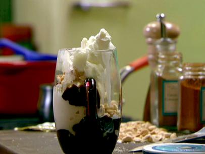 A close up of a sundae in a dessert glass. This sundae was made with hot fudge mixed with ground cinnamon and cayenne pepper. The vanilla ice cream was topped with the fudge sauce, almonds, and homemade whipped cream.