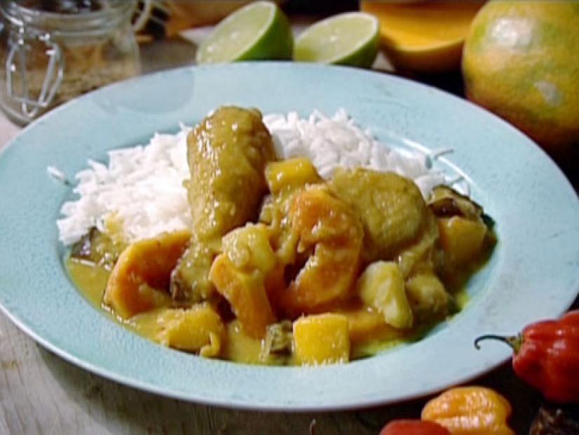 Martinique coconut chicken curry is served with a bed of rice. Pieces of mango and papaya are mixed into the chicken curry.