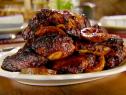 Grilled barbeque chicken is served on a white, oval platter.