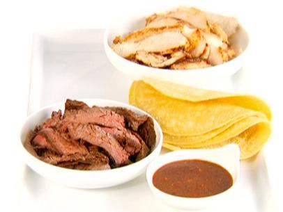 Chicken and steak fajitas are served with warmed tortillas and a bowl of sauce.
