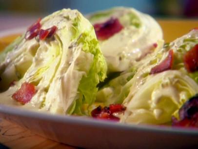 Wedges of iceberg lettuce are drizzled with a spicy ranch dressing and bits of bacon.
