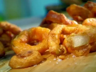 Sweet n smokey onion rings are covered in a batter consisting of smoked sweet paprika before frying.