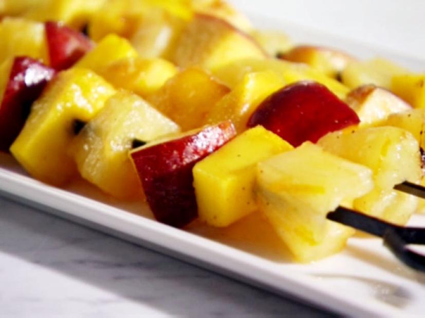 Chunks of pineapple, nectarines, and mango are grilled and served on a white platter.