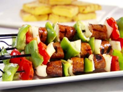 Hot Italian sausage, red and green bell peppers, and onions are grilled on skewers and served with grilled polenta.