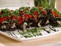 Grilled eggplant is rolled with goat cheese and topped with roasted red peppers, chopped parsley leaves, and drizzled with balsamic vinegar.