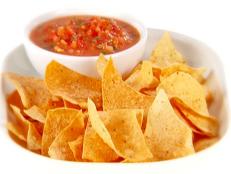 Spicy tomato salsa is served with tortilla chips on a white platter.