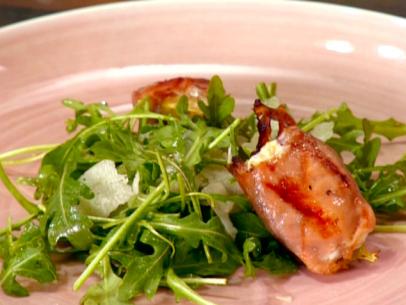 Grilled prosciutto wrapped figs are stuffed with goat cheese and served over a small plate of baby arugula.