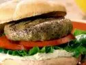 Mexican shrimp burgers are served with slices of tomato, lettuce, and a dollop of avocado aioli on a bun.