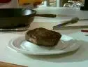 A pan seared rib eye rests on a platter.