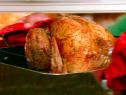 The turkey with holiday rub rests in the roasting pan.