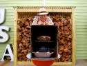 Alton Brown stands behind his homemade smoker that he is using to cook his pork shoulder.