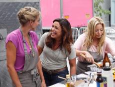 Host/Team Leader Rachael Ray (center) checks in with Contestants Summer Sanders (left) and Taylor Dayne (right) about their dishes for the Lunch Carts challenge as seen on Episode 4 of Food Network's Rachael Vs. Guy Season 1
