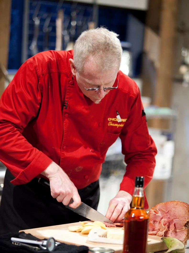 Chef Kenneth Johnson slices ham, as seen on Food Network’s Chopped Champions, Season 14.
