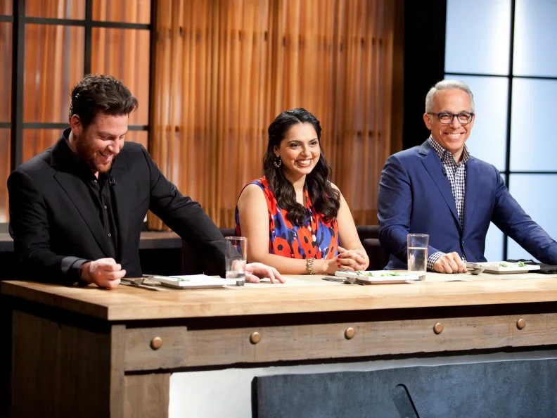 Judges Scott Conant, Maneet Chauhan, and Geoffrey Zakarian taste contestant dishes, as seen on Food Network’s Chopped Champions, Season 14.