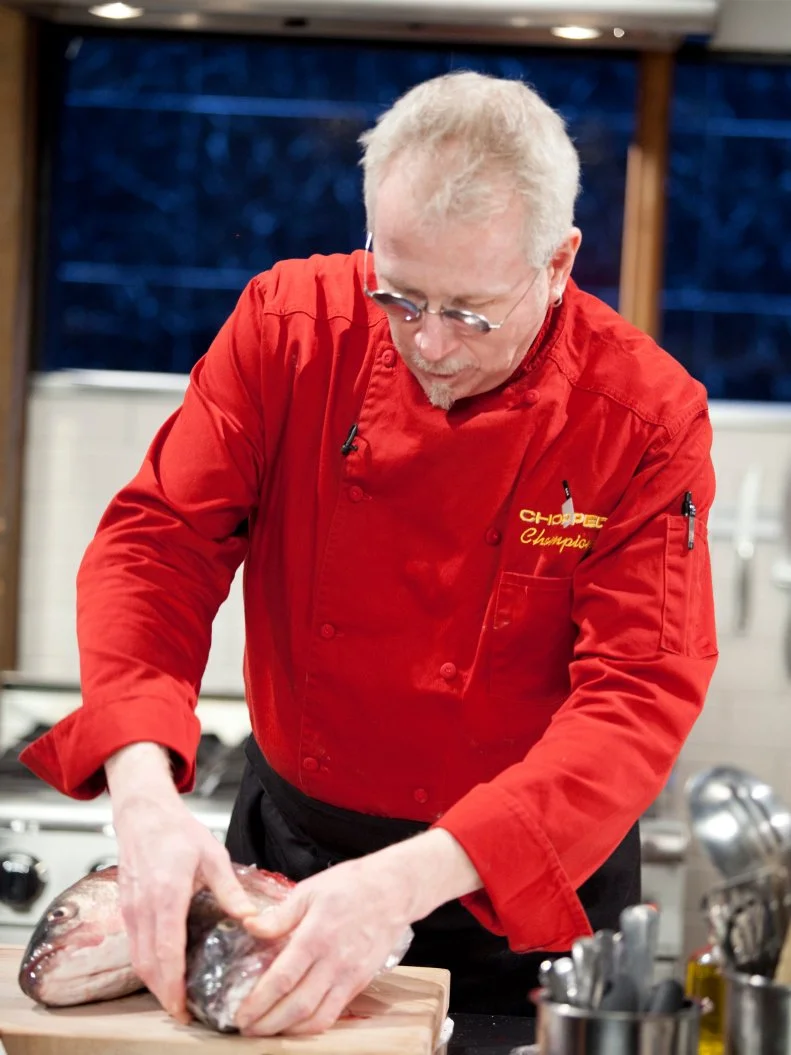 Chef Kenneth Johnson breaks down a fish, as seen on Food Network’s Chopped Champions, Season 14.
