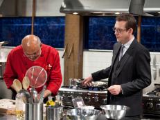 Host Ted Allen checks in with Chef Walter D'Rozario, as seen on Food Network’s Chopped Champions, Season 14.
