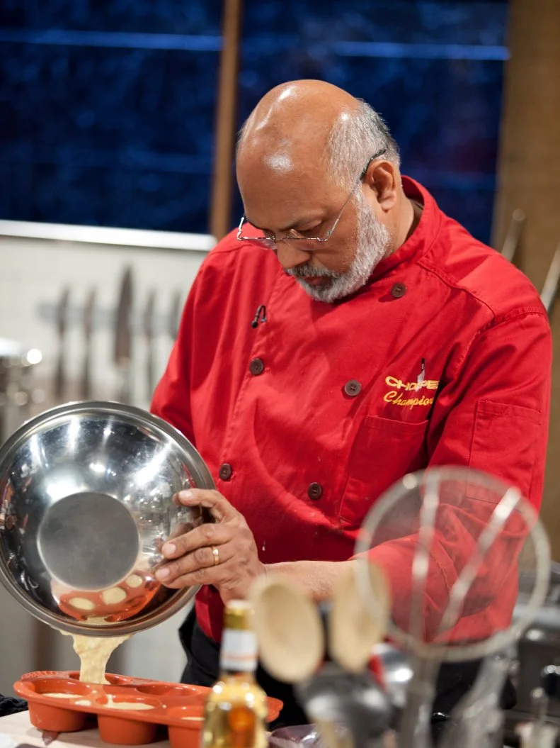 Chef Walter D'Rozario pours batter into muffin cups, as seen on Food Network’s Chopped Champions, Season 14.
