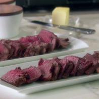 Filet mignon is sliced and served on white platters.