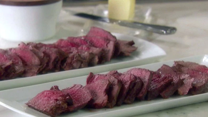 Filet mignon is sliced and served on white platters.