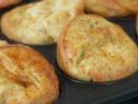 Garlic and cheese popovers cool in a muffin pan.