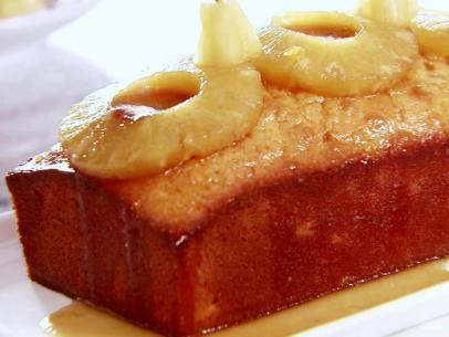 A close up of a pineapple pound cake that has been topped with pineapple and sauce.