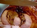 A knife sets on top of the turkey roulade after there has been once slice already cut.