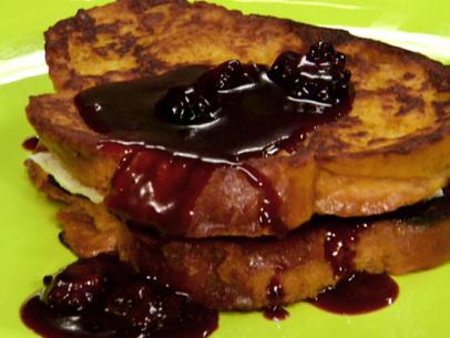 A french toast sandwich is served with a berry sauce.