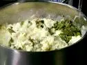 A pot with yukon gold mashed potatoes that have been combined with sour cream, butter, pepper jack cheese, and roasted peppers.