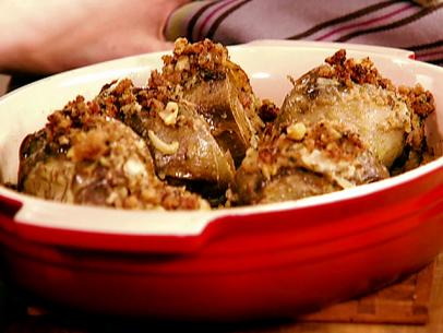 A red dish with stuffed and roasted artichokes inside. These artichokes have been stuffed with a mixture of cubed fontina cheese, parsley, fresh fennel, bread crumbs, and olive oil.
