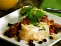 A square plate with a dish of phyllo wrapped huevos rancheros and a side of zesty guacamole. The filling was made with scrambled eggs, black beans, and queso fresco.