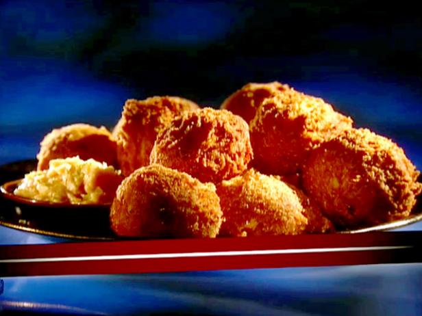 A platter of hoppy hush puppies piled on top of each other. These are golden fried corn dumplings that are served with spicy agave butter.