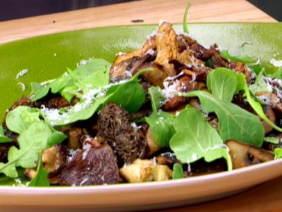 A grilled mushroom salad with arugula, shaved parmesan cheese, and truffle oil. This dish uses shiitake, oyster, cremini, sliced morels, and chanterelle mushrooms.