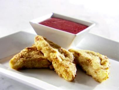 A platter with three matador triangles made from fried custard. There is also a small bowl of dipping fruit sauce.