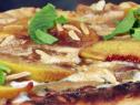 A Grilled Peach and Cajeta Pizza is garnished with fresh mint.
