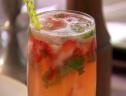 A close of a strawberry lemonade made with fresh strawberries, aquave nectar, lemon juice, seltzer, and fresh mint served in a glass.