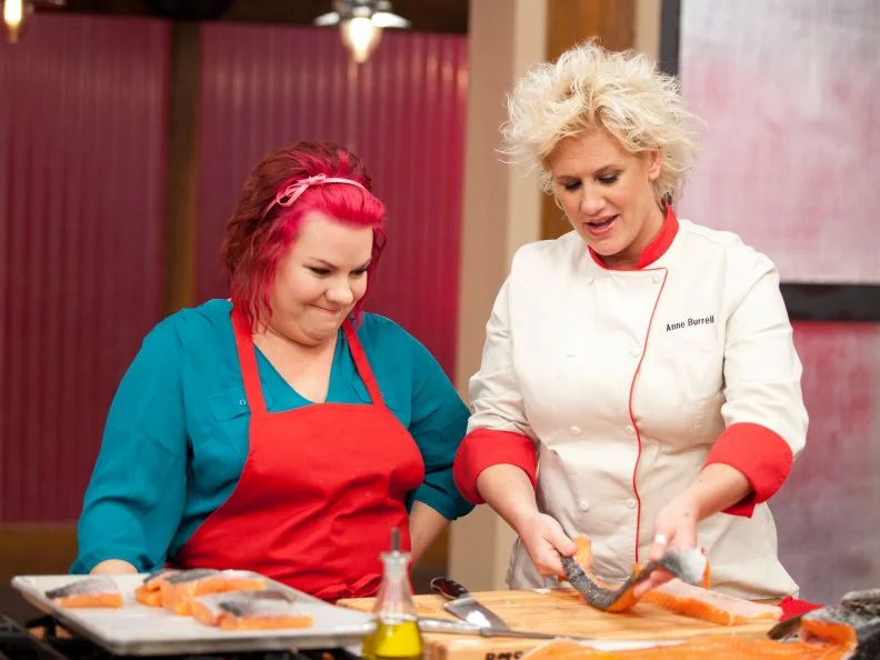 Chef Anne Burrell checks Dorothy Strouhal's fish filets during the Everything Seafood Challenge as seen on Food Network's Worst Cooks in America, Season 3.