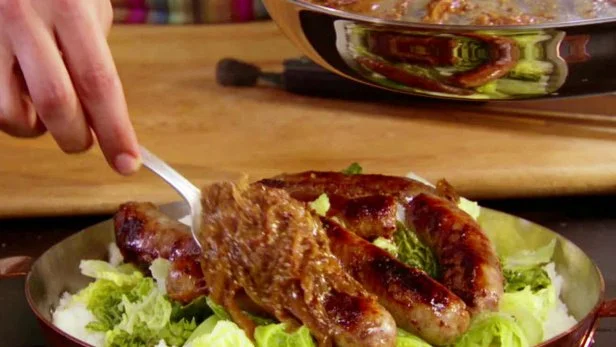 A dish of bangers and mash made with sausage, potatoes, cabbage, and carmelized onions