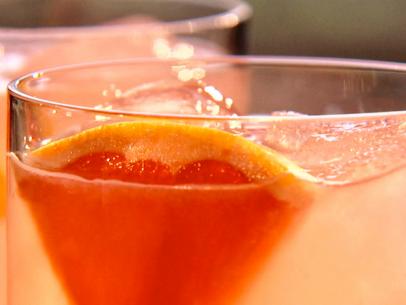 A close up of a glass with grapefruit gimlet cocktail garnished with a piece of fresh grapefruit.