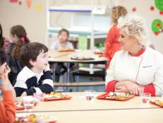 Chef Anne Burrell and elementary school students taste the healthy and kid-friendly cafeteria food made by the recruits in the Cooking for Kids Challenge as seen on Food Network's Worst Cooks in America, Season 3.
