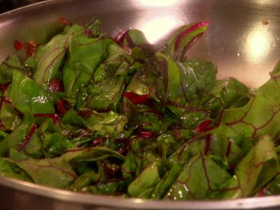 Garlicky Sautéed Swiss Chard is tossed in a stainless steel bowl.